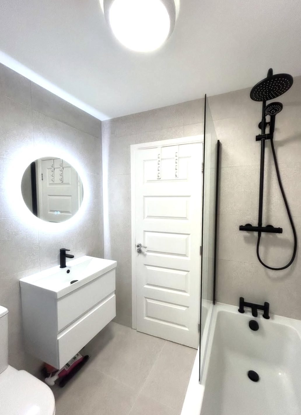 White bathroom with large format tiles and matt black shower over bath